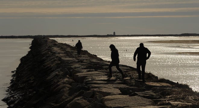 PROVINCETOWN -- The late morning sun silhouettes those few who braved the cold temperatures to walk on the breakwater in the West End on Jan. 11, 2015.