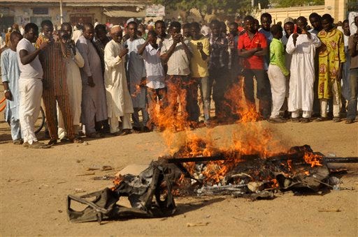 In this file photo taken on Friday, Nov. 28, 2014, People gather at the site of a bomb explosion in a area know to be targeted by the militant group Boko Haram in Kano, Nigeria. Boko Haram leader Abubakar Shekau has claimed responsibility for the mass killings in the northeast Nigerian town of Baga and threatened more violence. As many as 2,000 civilians were killed and 3,700 homes and business were destroyed in the Jan. 3, 2015, attack on the town near Nigeria's border with Cameroon, said Amnesty International. (AP Photo/Muhammed Giginyu, File)
