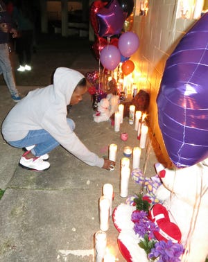 Diamond Green sets a candle down at a memorial and candlelight vigil in Crestview for 18-year-old Mark Anthony Williams, who was found dead earlier this week.