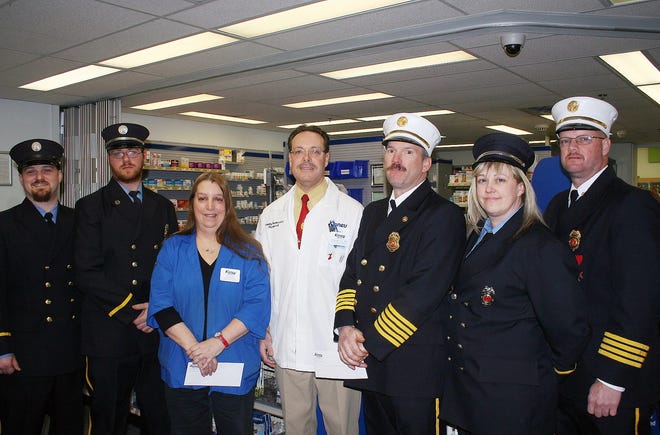 Kinney Drugs Favorite Pharmacist of the Year Tim Baumeiser, center, presented $500 donations to the H.C. Smith Benefit Club and the St. Johnsville Volunteer Fire Department Monday afternoon in recognition of all they do for the community. Baumeister, pharmacist at the St. Johnsville Kinney Drugs store, won the distinction last month and received a $1,000 gift to donate to a charity of his choice. He chose to split the award and give $500 each to the fire department and benefit club. Cathy Rice, center left, received the donation on behalf of the benefit club and Fire Chief Chris Weaver, center right, received the donation on behalf of the fire department. Also pictured are other members of the St. Johnsville Volunteer Fire Department. TIMES PHOTO/ROB JUTEAU