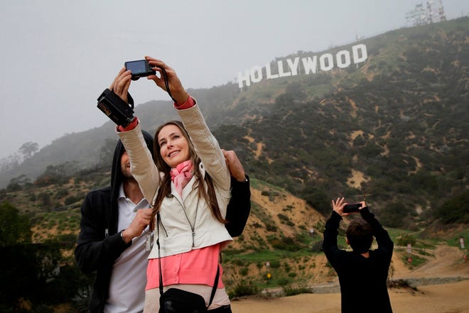 Brazilian tourist Marcela Lucato takes a selfie with her husband, Junior, as their son, Mikhael, takes pictures of the Hollywood Signlast week in Los Angeles.