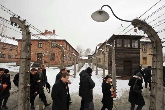 Visitors walk by barbed wire fences at the Auschwitz Nazi death camp in Oswiecim, Poland, Monday, Jan. 26, 2015. A decade ago, 1,500 Holocaust survivors traveled to Auschwitz to mark the 60th anniversary of the death camp's liberation. On Tuesday, for the 70th anniversary, organizers are expecting 300, the youngest in their 70s. (AP Photo/Alik Keplicz)
