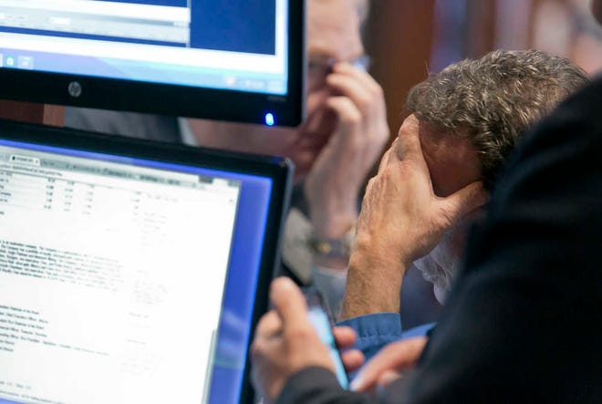 Traders work on the floor of the New York Stock Exchange. U.S. stocks tumble in midday trading, weighed down by forecasts and a drop in orders of long-lasting goods.