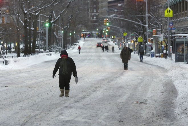 People walk on Broadway, avoiding snow covered sidewalks, on the Upper West Side, in New York this morning.