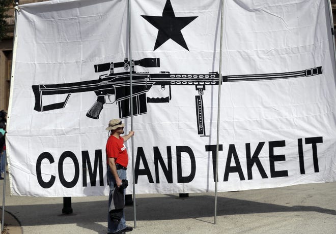 A man helps hold a banner at a rally for open-carry gun laws at the Texas Capitol in Austin. Yesterday's rally drew about 75 people; some carried bananas or rolled-up copies of the Constitution in their holsters, according to the Abilene Reporter-News.