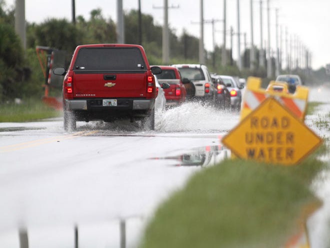 Cars slow down as they heed a warning of rising water on a stretch of River Road Tuesday Sept. 24, 2013 in North Port. Local flooding came with a system that dumped massive amounts rain in the area with more expected over the next few days.