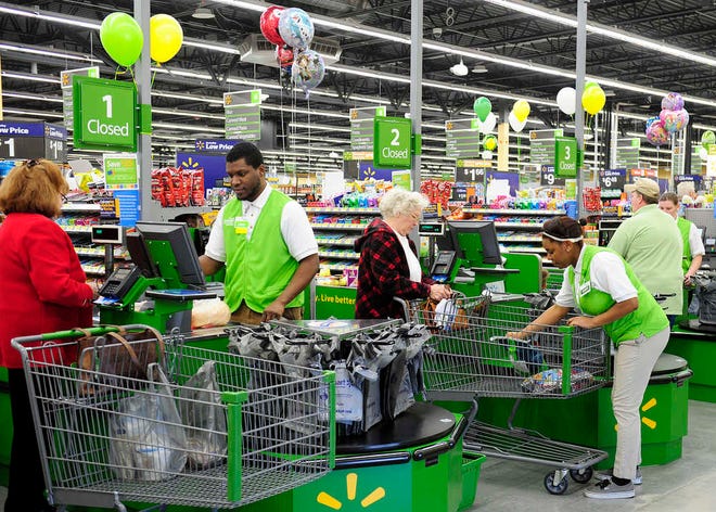 Walmart Neighborhood Market cashiers help customers at the new location on South Belair Road during their grand opening day.