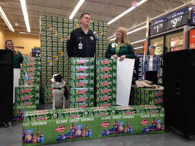 David Meek, founder of the Kansas Search and Rescue Dog Association, receives a $1,000 check for the organization from Walmart Neighborhood Market store manager Veronica Mangiaracino on Wednesday morning at the new Topeka location at 335 S.W. MacVicar. Also pictured is Meek's canine companion Wiley, a border collie.