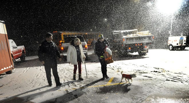 Denise Galvin, right, of the Cape Cod Medical Reserve Corps, helps Margi Durkin, of South Yarmouth, and her dog Lily into the emergency shelter at Dennis-Yarmouth Regional High School on Monday night. Galvin and other shelter volunteers worked many hours with little sleep during the storm.
