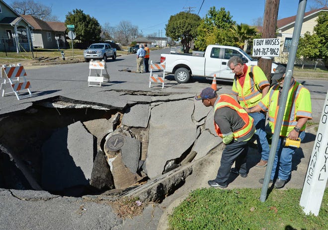 Beaumont crew workers tend to a sinkhole that appeared Tuesday, Jan. 27, 2015 in Beaumont, Texas. Engineers in Beaumont say it could take a couple of weeks to repair the hole that opened Tuesday. Beaumont traffic engineer Zheng Tan Tan says a possible storm sewer line rupture probably caused the sinkhole in a neighborhood. (AP Photo/The Beaumont Enterprise, Guiseppe Barranco)
