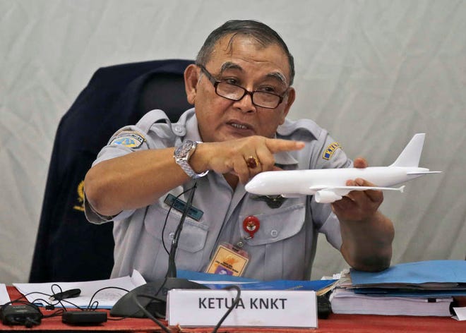 Indonesian National Transportation Safety Committee chief Tatang Kurniadi speaks with a model plane of AirAsia Flight 8501 that crashed into the Java Sea on Dec. 28 last year during a press conference in Jakarta, Indonesia Thursday, Jan. 29, 2015. Indonesian investigators announced Thursday the co-pilot of the AirAsia jet was in controls when he struggled to recover the aircraft as stall warnings sounded. (AP Photo/Dita Alangkara)