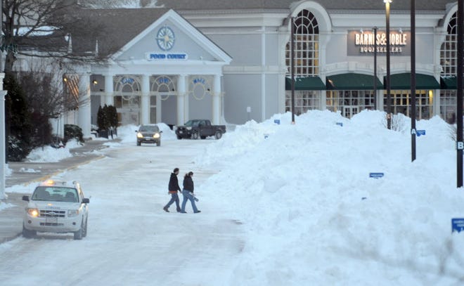 Hyannis -- Cape Cod Mall customers make their way to their car amongst the piles of snow Wednesday evening.