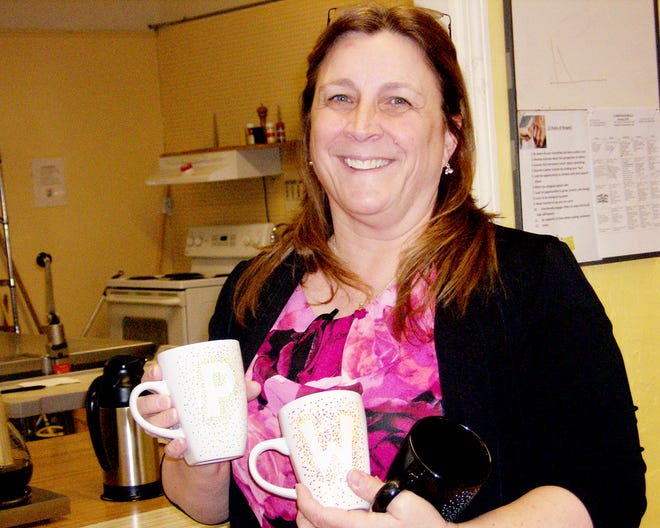 Deb Goodsell holds mugs she personalized for some of the regulars at the Clinton Senior Center.