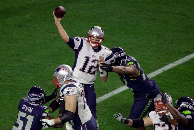 New England quarterback Tom Brady delivers a pass Sunday as he is hit by Seattle defensive end Michael Bennett during the second half.