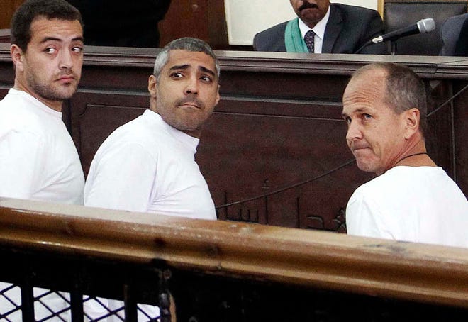 FILE - In this Monday, March 31, 2014 file photo, Al-Jazeera English producer Baher Mohamed, left, Canadian-Egyptian acting Cairo bureau chief Mohammed Fahmy, center, and correspondent Peter Greste, right, appear in court along with several other defendants during their trial on terror charges, in Cairo, Egypt. senior Egyptian prison official and the country's official news agency said Sunday, Feb. 1, 2015, that Al-Jazeera's Australian reporter Peter Greste has been freed from prison. A Cairo airport official says Greste has left Egypt on a flight to Cyprus after his release from prison. The agency said his release on Sunday, after more than a year behind bars, followed a presidential "approval" and both said it was coordinated with the Australian Embassy in Cairo. (AP Photo/Heba Elkholy, El Shorouk, File) EGYPT OUT