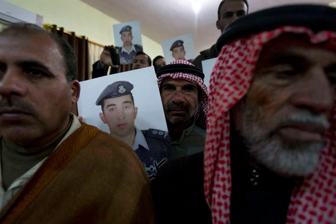 Members of Al-Kaseasbeh, the tribe of Jordanian pilot, Lt. Muath al-Kaseasbeh, who is held by the Islamic State group militants, carry posters with his picture and Arabic that reads "we are all Muath," at the captured pilot's tribal gathering divan, in his home town of Karak, Jordan, Saturday, Jan. 31, 2015. An online video released Saturday night purported to show an Islamic State group militant behead Japanese journalist Kenji Goto, ending days of negotiations by diplomats to save the man. (AP Photo/Nasser Nasser)