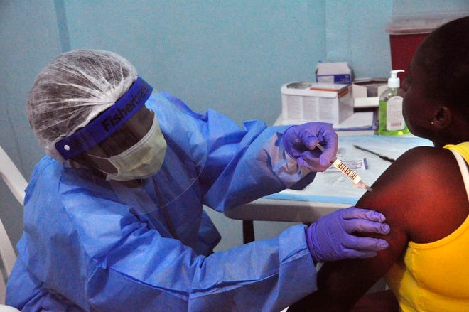 A woman, right, is injected by a health care worker, left, as she takes part in a Ebola virus vaccine trial at one of the largest hospital's Redemption hospital in Monrovia, Liberia, Monday, Feb. 2, 2015. A large-scale human trial of two potential Ebola vaccines got under way in Liberia's capital Monday, part of a global effort to prevent a repeat of the epidemic that has now claimed nearly 9,000 lives in West Africa. (AP Photo/ Abbas Dulleh)
