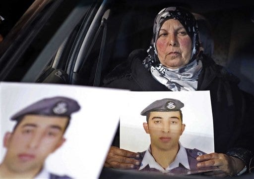 FILE - In this Tuesday, Jan. 27, 2015 file photo, the mother of Jordanian pilot Lt. Mu'ath al-Kaseasbeh holds a picture of her son, who is held by Islamic State group militants, in a car during a sit-in in front of the cabinet offices in Amman, Jordan. An online video released Tuesday, Feb. 3, 2015 purportedly shows a Jordanian pilot captured by the Islamic State extremist group being burned to death. The Associated Press was not immediately able to confirm the authenticity of the video, which was released on militant websites and bore the logo of the extremist group's al-Furqan media service. (AP Photo/Raad Adayleh, File)