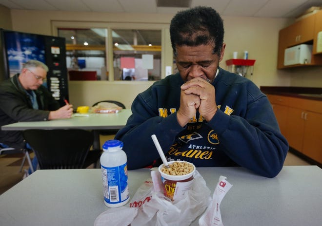 In this Jan. 9, 2015, photo, James Robertson, 56, of Detroit, prays before eating in the break room before his shift at Schain Mold & Engineering in Rochester Hills, Mich. Getting to and from his factory job 23 miles away, Robertson takes a bus partway there and partway home and walks 21 miles according to the Detroit Free Press.