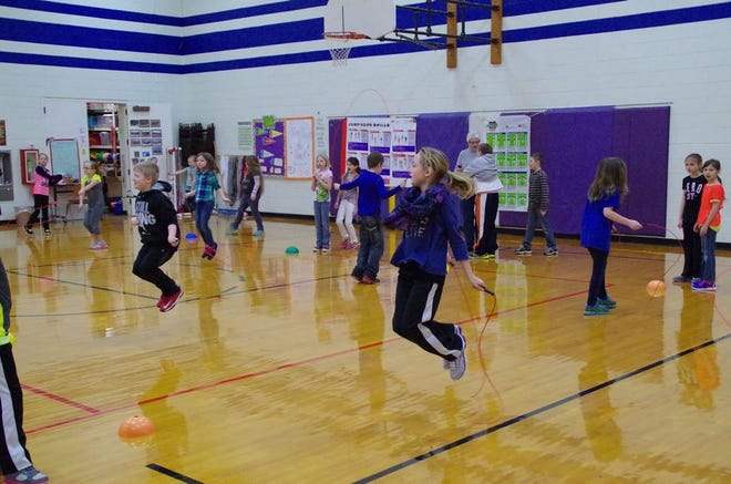 Small groups of third graders are taking turns jumping a single jump rope.