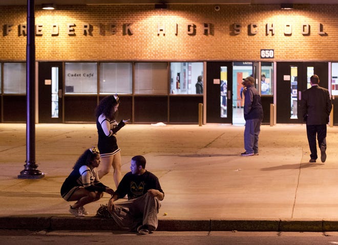 People gather outside the entrance to Frederick High School following a shooting in Frederick, Md., Wednesday, Feb. 4, 2015.