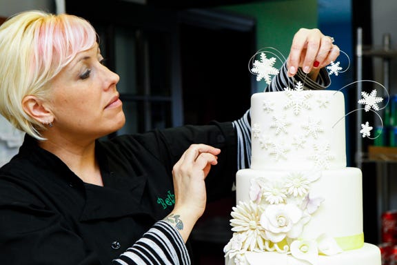 Beth DiBenedetto, owner of White Oak Bakery, adjust the snow flakes a the top of a Four Season Wedding cake at White Oak Bakery on Piney Green Road Wednesday.
