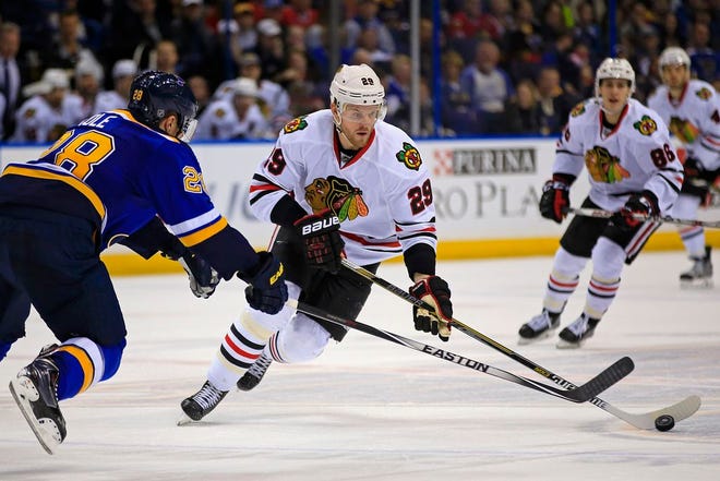 Chicago Blackhawks' Bryan Bickell, front right, brings the puck down the ice as St. Louis Blues' Ian Cole defends during the first period of an NHL hockey game Sunday, Feb. 8, 2015, in St. Louis.