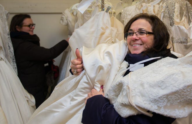 Joyce Hughes (right), holds an armful of dresses for her daughter Charlolette at last year's bridal gown sale.