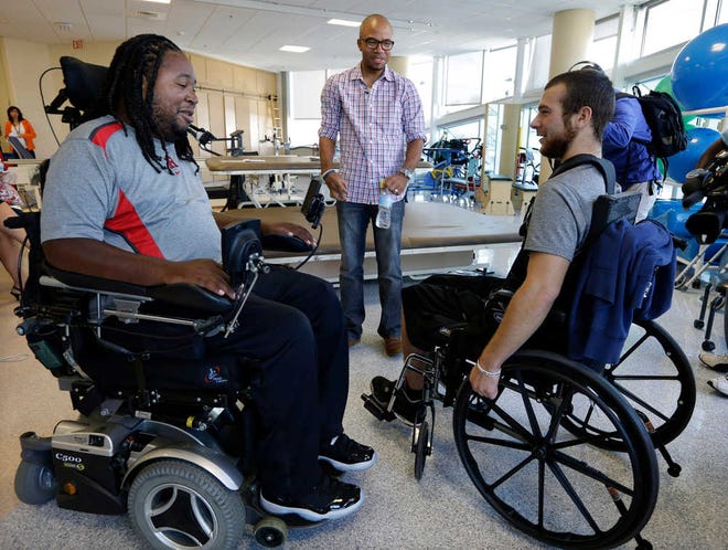 FILE - In this Wednesday, Sept. 10, 2014 file photo, Eric LeGrand, left, alumni of Rutgers University and Adam Taliaferro, center, alumni of Penn State University, both college football players who suffered serious spinal cord injuries on the field, talk with Jonathan Ulassin, 19, while visiting children at PSE&G Children's Specialized Hospital in New Brunswick, N.J. Taliaferro is a newly minted New Jersey state lawmaker. It is the latest step in a rapid rise up the public service ladder for a political neophyte who says he is motivated by helping others. (AP Photo/Mel Evans,file)