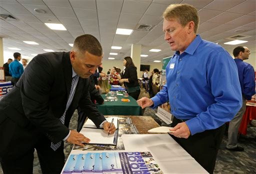 In this Friday, Feb. 6, 2015 photo, U.S. Marine Corps veteran Ignacio Yanes, left, writes information given by Jim Brooks, right, of the Small Business Administration at the annual Veterans Career and Resource Fair in Miami. The Labor Department issues its December report on job openings and labor turnover on Tuesday, Feb. 10, 2015. (AP Photo/Alan Diaz)