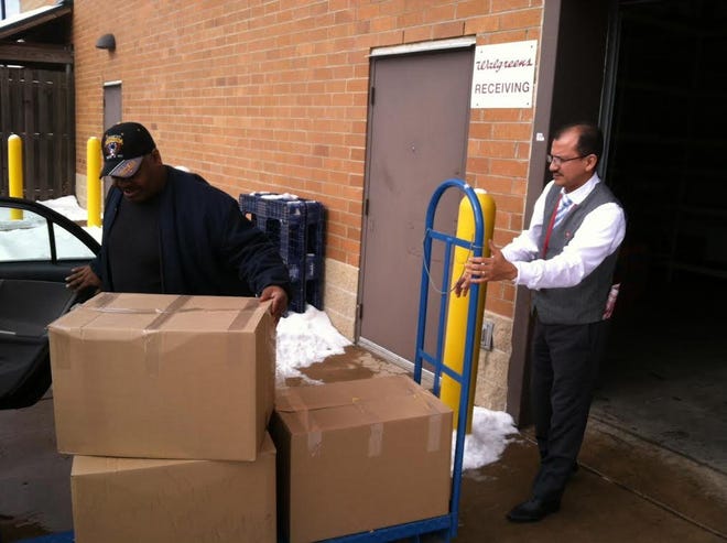 The Rev. Christopher Boone of Tobyhanna; left; loads boxes of snacks; donated by Walgreens pharmacy in Stroudsburg; into his car to take with him on an upcoming trip to South Africa; where he plans to help the less fortunate. Providing the donated snacks is Walgreens Manager Dave Arias. (Andrew Scott; Pocono Record)