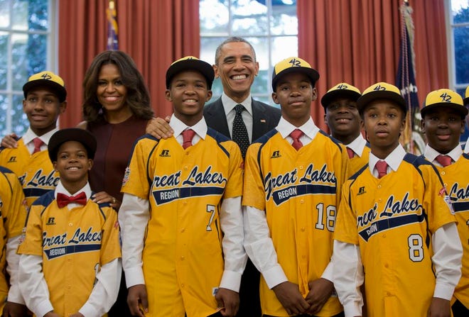 In this Nov. 6, 2014, file photo President Barack Obama and first lady Michelle Obama pose with members of the Jackie Robinson West little league team in the Oval Office of the White House in Washington. Little League International has stripped Chicago's Jackie Robinson West team of its national title after finding the team falsified its boundary map. The league made the announcement Wednesday morning, Feb. 11, 2015, saying the Chicago team violated regulations by placing players on the team who didn't qualify because they lived outside the team's boundaries. Little League International also suspended Jackie Robinson West manager Darold Butler from league activity. (AP Photo/Pablo Martinez Monsivais, File)