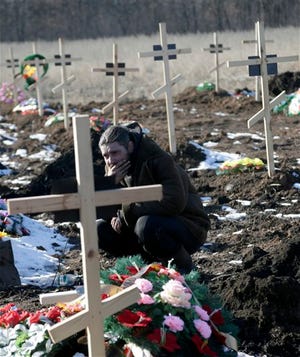A mourner pays his respects to a Russia-backed separatists fighter during a funeral at a cemetery in the east Ukrainian village of Mospino, near the city of Donetsk, Ukraine, on Thursday, Feb. 12, 2015. The militiaman was killed during recent fighting between Russia-backed separatists and government forces. Guns will fall silent, heavy weapons will pull back from the front, and Ukraine will trade a broad autonomy for the east to get back control of its Russian border by the end of this year under a peace deal hammered out Thursday after all-night negotiations between Russia, Ukraine, France and Germany. (AP Photo/Petr David Josek)