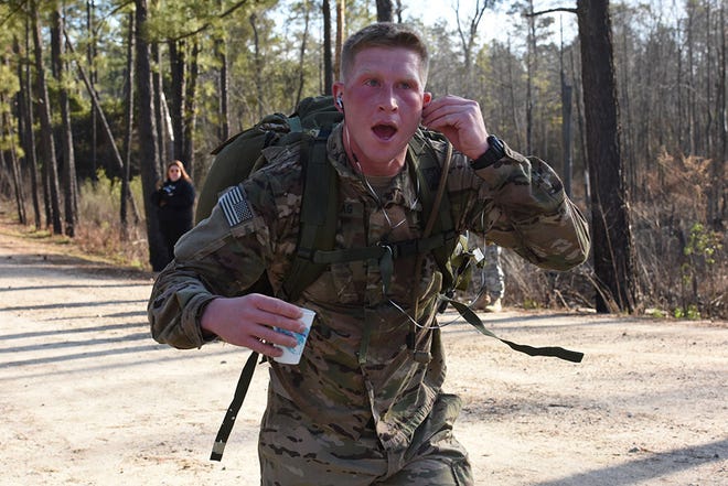 Miles Sunntag, Headquarters and Headquarters Company, 1st Battalion 325th Airborne Infantry Regiment, fixes his head phones after grabbing a cup of water during the Combat Cross Country Meet at Smith Lake, Feb. 7. Suntag finished third in the men division with a time of 1:40:34.