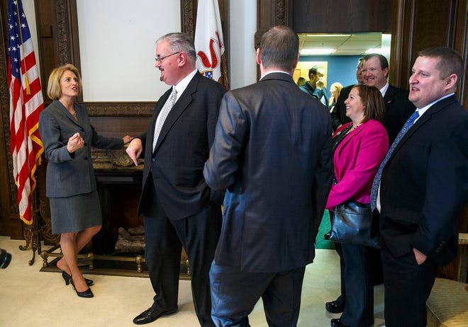 In this Jan. 12, 2015 photo, lllinois Comptroller Leslie Munger, left, greets visitors during a reception in her office at the State Capitol in Springfield after she was inaugurated. Munger sees her new job as a chance to help the state get its budget problems in order. Republican Gov. Bruce Rauner appointed Munger to replace Judy Baar Topinka, who died last year after winning another term as comptroller. (AP Photo/The State Journal-Register, Ted Schurter)