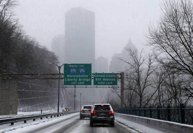 Falling snow obscures the Pittsburgh skyline as traffic makes its way through the snowstorm in Pittsburgh on Saturday.