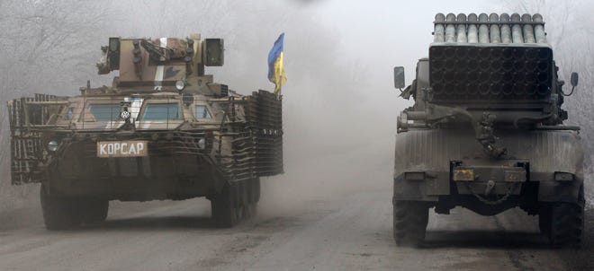Ukrainian military vehicles travel on the road between the towns of Dabeltseve and Artemivsk, Ukraine, Saturday.