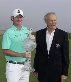 Brandt Snedeker holds his trophy and poses with Clint Eastwood on the 18th green of the Pebble Beach Golf Links after winning the AT&T Pebble Beach National Pro-Am golf tournament Sunday in Pebble Beach, Calif. Snedeker won the tournament after shooting a 5-under-par 67 to finish at total 22-under-par. AP Photo/Eric Risberg