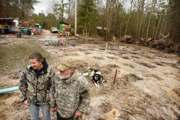 Reservist Amanda Pavone stands with Vietnam War veteran Donald Lee in front of where Lee's new home is being built. Pavone used Facebook to rally volunteers to build the cabin so that he would not have to continue living in an unheated camper.