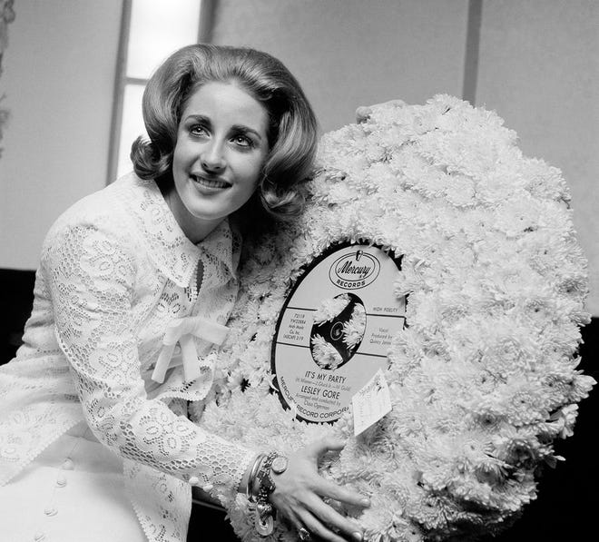 FILE - In this May 5, 1964, file photo, singer Lesley Gore hugs a flowered record at her 18th birthday party celebrated at the Delmonico Hotel in New York. Singer-songwriter Gore, who topped the charts in 1963 with her epic song of teenage angst, "It's My Party," and followed it up with the hits "Judy's Turn to Cry," and "You Don't Own Me," died of cancer, Monday, Feb. 16, 2015. She was 68. (AP Photo/Marty Lederhandler, File)