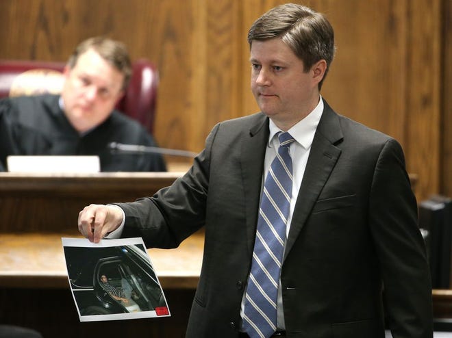 Erath County District Attorney Alan Nash carries a photo of former Marine Cpl. Eddie Ray Routh handcuffed in the back of a Lancaster Police car the night of his arrest, during Routh's capital murder trial at the Erath County, Donald R. Jones Justice Center in Stephenville, Texas, Friday, Feb. 13, 2015. Routh, 27, of Lancaster, is charged with the 2013 deaths of former Navy SEAL Chris Kyle and his friend Chad Littlefield at a shooting range near Glen Rose, Texas. The photo, made by Texas Ranger David Armstrong, was offered as evidence by Nash. (AP Photo/The Fort Worth Star-Telegram, Paul Moseley, Pool)