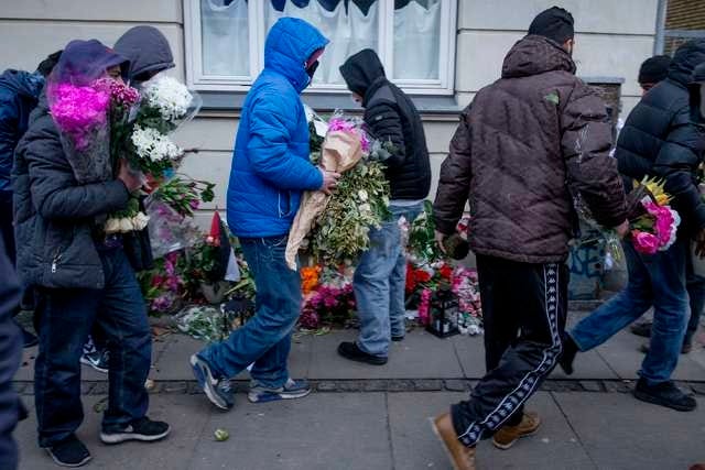 People who knew the gunman remove flowers laid at the place where he was killed by police, on Svanevej Street in Copenhagen February 16, 2015. Danish police have arrested two people on suspicion of aiding the gunman in deadly attacks on a synagogue and an event promoting free speech at the weekend that have shocked a nation proud of its record of safety and openness. The 22-year-old gunman opened fire on a cafe in Copenhagen hosting a free speech debate on Saturday, killing one, and attacked a synagogue, killing a guard. The man was later shot dead by police in his neighborhood of Norrebro, a poor and largely immigrant part of the city with a reputation for gang violence.   REUTERS/Jens Astrup/Scanpix