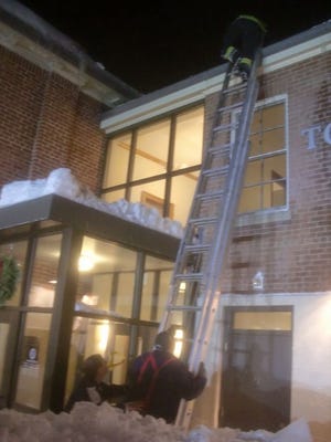 Firefighters cleared snow off the roof of Raynham Town Hall on Tuesday.