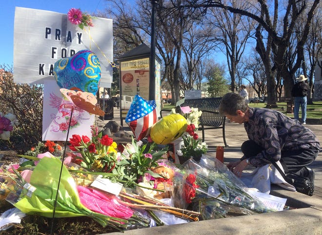 An unidentified woman kneels near a makeshift memorial for Kayla Mueller on Thursday, Feb. 12, 2015, in Prescott, Ariz.