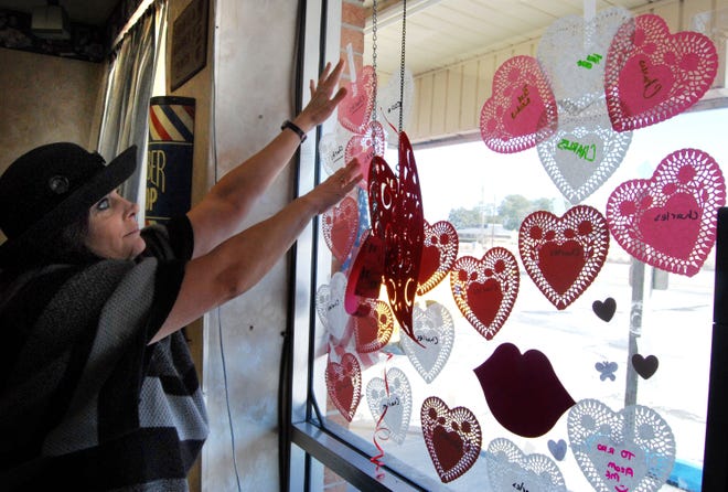 Tina Matson, owner of Total E-Clips Hair Salon in Havelock, puts up paper hearts that were sold to benefit Charles Finney, who suffers from a raise genetic disease. Finney is the son of Havelock Police Officer and former Marine Gaylan Finney and his wife Carrie Finney, a sales manager at Marine Corps Community Services at Cherry Point.