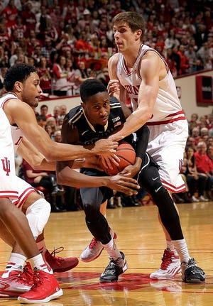 Purdue guard Jon Octeus, center, wrestles for control of the ball with Indiana defenders James Blackmon Jr., left, and Collin Hartman during the first half of an NCAA college basketball game in Bloomington, Ind., Thursday, Feb. 19, 2015.