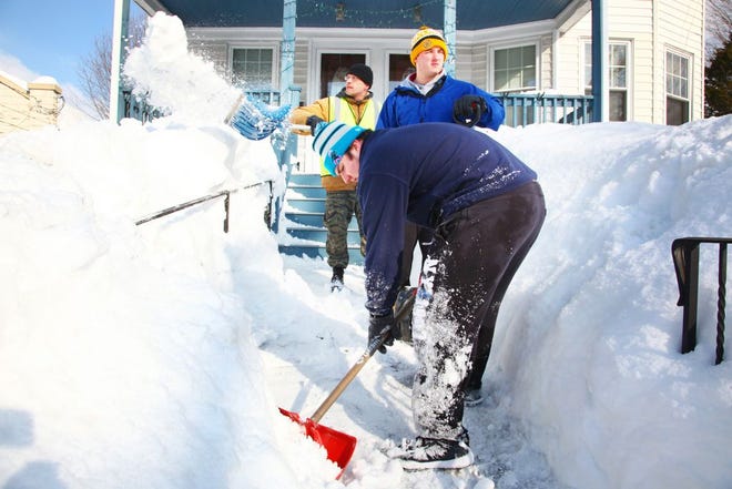 Volunteers, from foreground: Paul Conley, 16, of Pembroke High School, Oliver Pierce, 18, of Hingham High School and Bobby Grappi of Quincy, shovel out a home along Independence Avenue in Quincy. Quincy City Councilor Brian Palmucci organized a group of youth and parent volunteers to shovel out elderly around the city Thursday, Feb. 19, 2015.