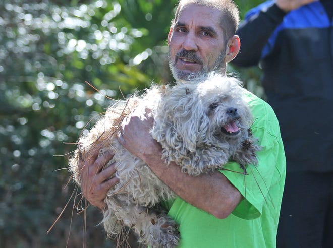 Mark Robertson carries his dog after leaving his burning house. No injuries were reported after a house caught fire off Baldwin Ave. in Hiland Park.