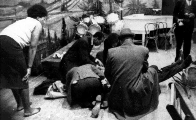 FILE- In this Feb. 21, 1965 file photo, Human rights activist Malcolm X is tended to as he lies mortally wounded on the stage of the Audubon ballroom in the Harlem section of New York after being shot multiple times. On Saturday, Feb. 21, 2015, the Malcolm X and R. Betty Shabazz Memorial and Educational Center will hold a ceremony to recognize the 50th commemoration of the assassination. (AP Photo/WCBS-TV)