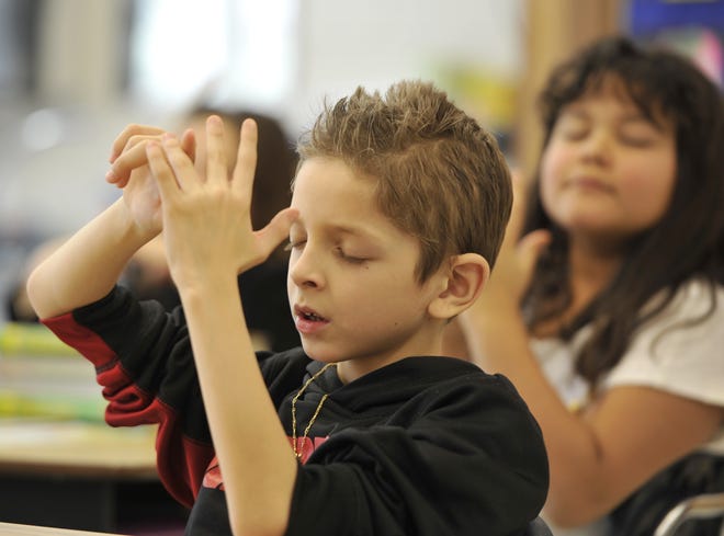Joao Victor Lopes works on his five finger breathing technique during Calmer Choice's session at the Hyannis West Elementary School. During five-finger breathing, children trace the thumb and fingers of an open hand with the pointer finger of the other hand, inhaling and exhaling as they trace each finger. This forces the breath to slow and the mind to focus on breathing. Steve Heaslip photos/Cape Cod Times